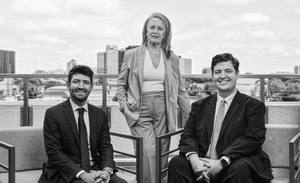 A group portrait of the three lawyers on a rooftop deck in front of the North Dallas skyline.